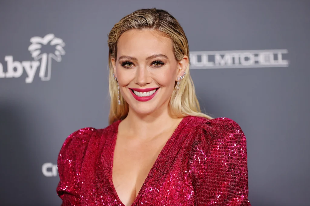 Smiling Hilary Duff in maroon shimmery dress posing for camera - hollywood dental implants
