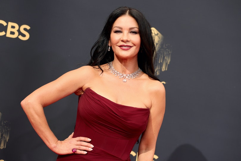 Catherine Zeta-Jones in maroon tube dress with silver jewellery posing fort camera - hollywood celebrities with dental implants 