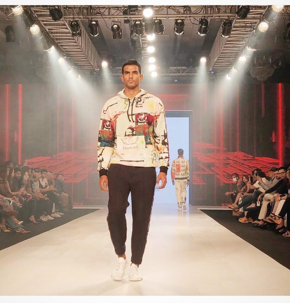 Taher Ali in multicolor printed sweatshirt with black trouser and white sneakers walking on a stage - top male models in India