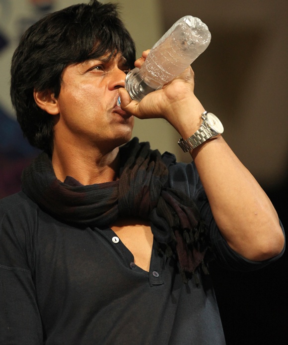 Shahrukh Khan in blue shirt and scarf drinking water with a bottle - Shahrukh Khan hair colour