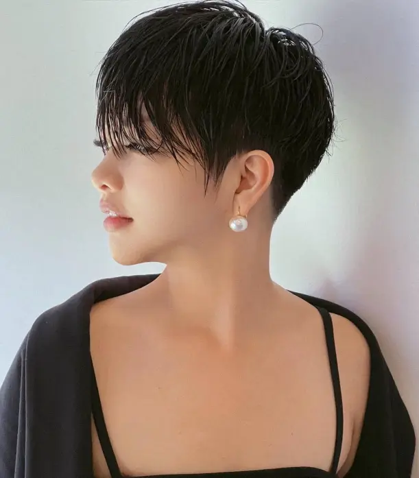 Woman in black strappy dress and shrug with pearl earring and Long Wispy Bangs hairstyle - short haircuts for round face