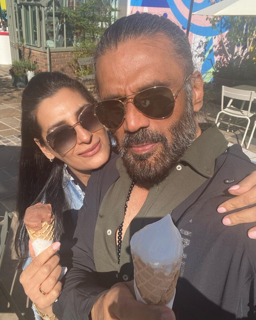 Suniel Shetty in blue jacket with goggles and Mana Shetty in blue jacket with googles holding ice creams and posing for a selfie - Leo compatibility