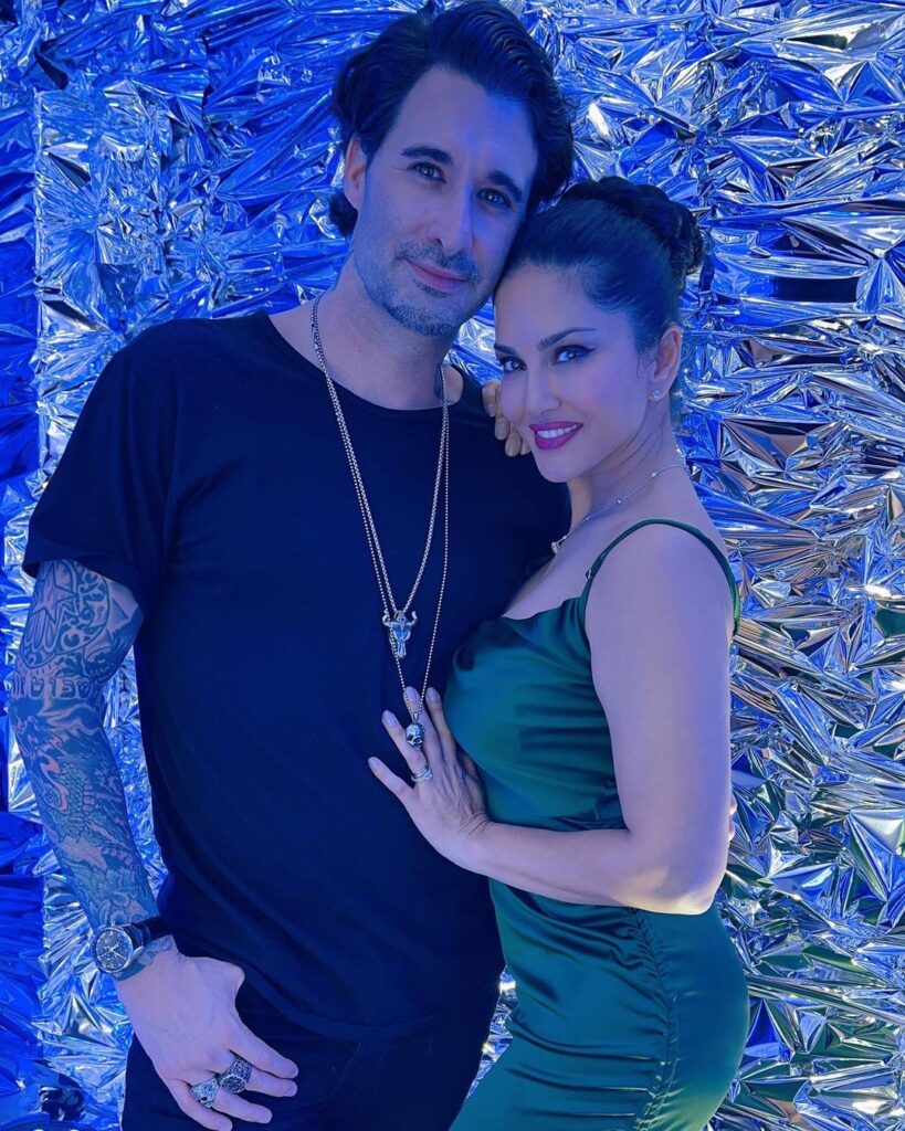 Sunny Leone in strappy green dress and Daniel Weber in black t-shirt with silver chains in his neck posing for camera - best match for Taurus