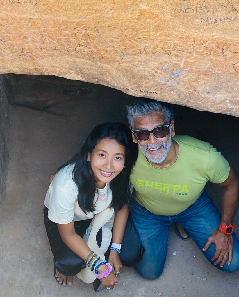 Milind Soman in green t-shirt with jeans Ankita in white t-shirt with black jeans sitting in a cave and posing for camera - Scorpio best compatibility