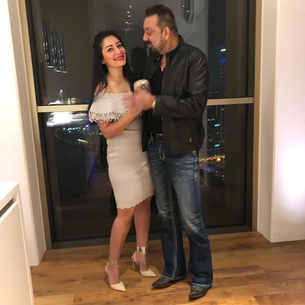 Sanjay Dutt in black jacket with blue jeans and Manyta in light grey short dress posing for camera - best match for Leo