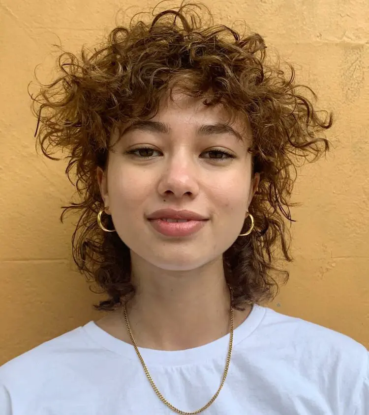 Woman in white round neck t-shirt with golden jewellery and The Curly Mullet - mullet haircut 2022