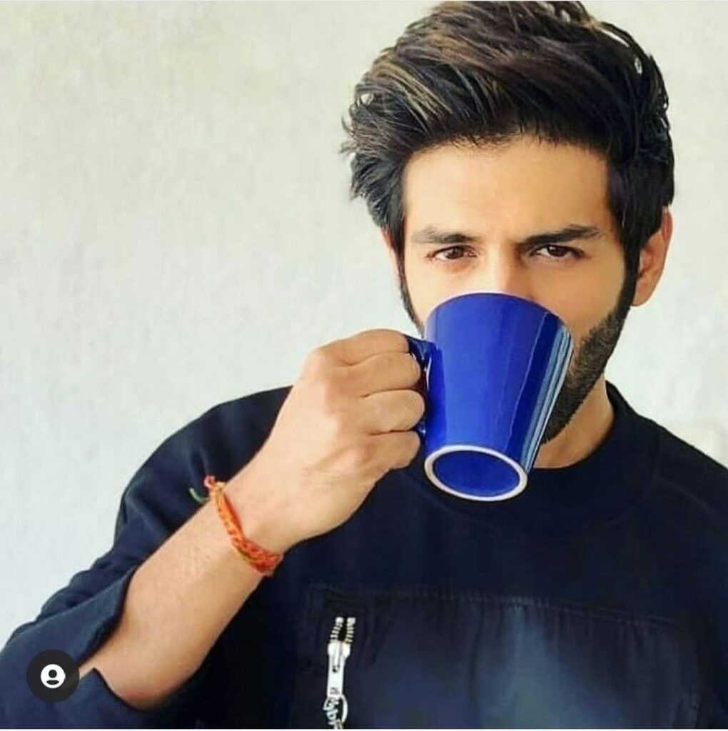 Kartik Aaryan in blue round neck t-shirt sipping some drink from a blue mug - Kartik Aaryan hair care