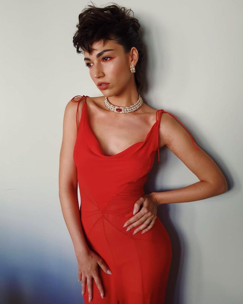 Woman in red cut sleeves body con dress with matching jewellery and Punk Mullet hairstyle - mullet haircut 2022