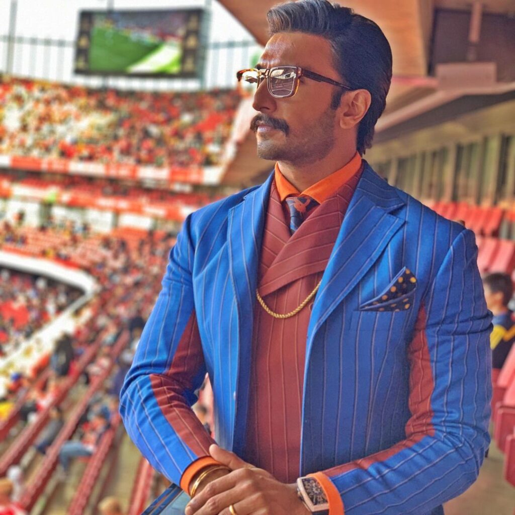 Ranveer Singh in blue and brown suit with orange shirt and matching tie with goggles - Ranveer Singh beard