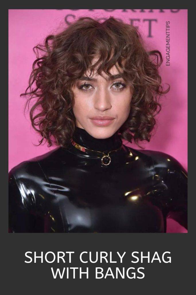 Woman in black high neck shiny body suit  and short curly shag with bangs - shag haircuts for women