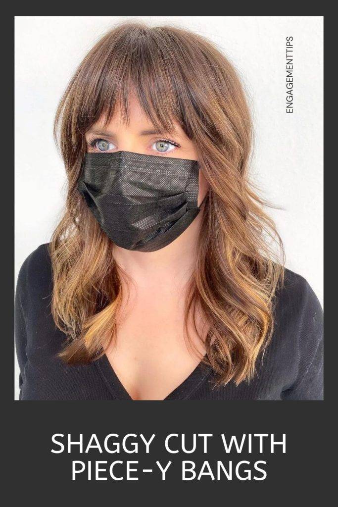 Woman in black v-neck top and mask and showing her shaggy cut with piece-y bangs - Modern shag haircut