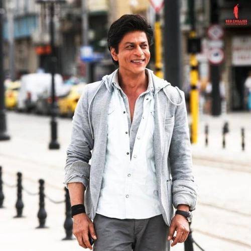 Shahrukh khan in white t-shirt and grey shrug with side parted medium hairstyle