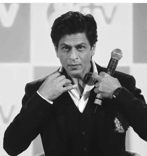 Shahrukh khan in in black suit with white shirt with vintage hairstyle