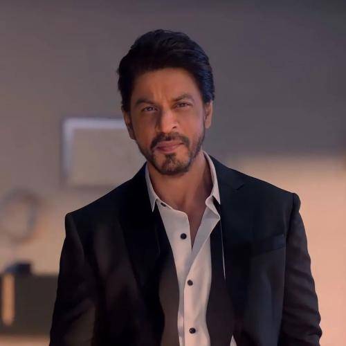 Shahrukh khan in black suit with white shirt and ponytail hairstyle